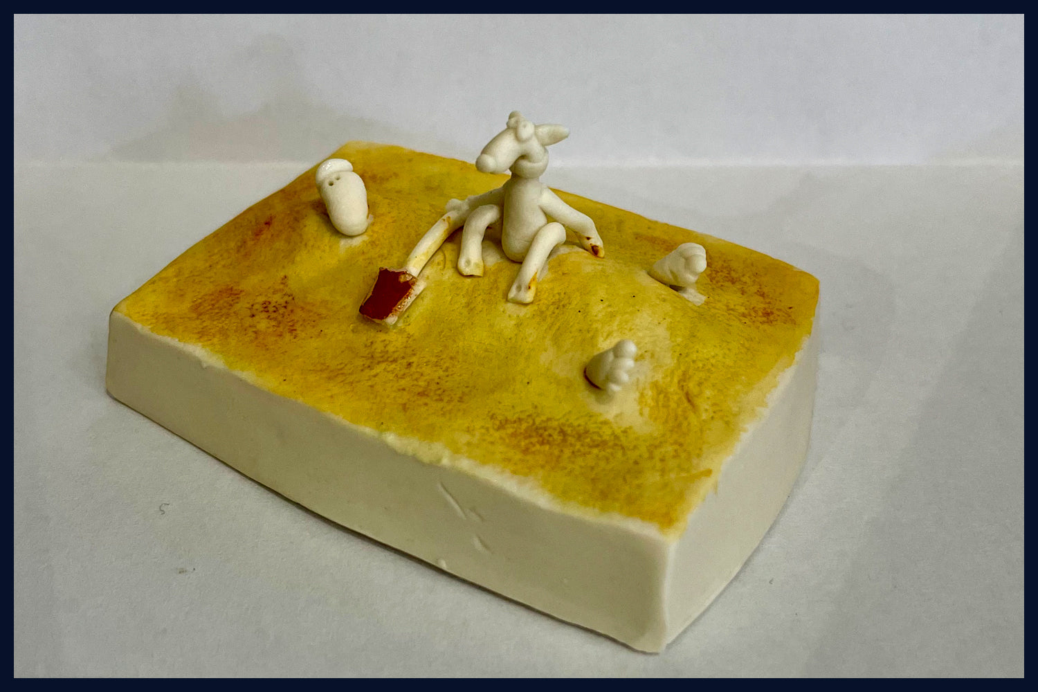 Ceramic Miniaturist Andrew Bull - man buried in sand on the beach
